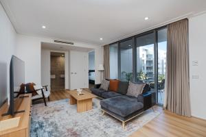 a living room with a couch and a tv at Modern 1-Bed Unit with Pool Views and Balcony in Canberra