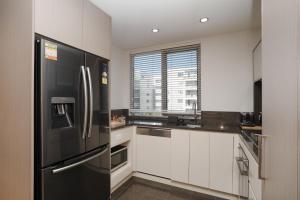a kitchen with a black refrigerator and white cabinets at Modern 1-Bed Unit with Pool Views and Balcony in Canberra