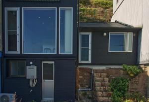 a black house with a blue door and windows at 壇ノ浦ハウス in Shimonoseki