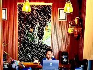 un homme assis à une table en utilisant un ordinateur portable dans l'établissement Wait Garden Cottage, à Nusa Penida
