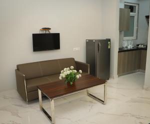 古尔冈The Empire Corporate Villa Hotel Sector 29 near Fortis and Max Hospitals,Huda City Metros Station的客厅里有一张沙发和一张摆满鲜花的桌子