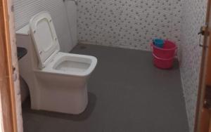 une salle de bain avec toilettes et poubelle rouge dans l'établissement Jaldapara Eco Resorts by StayApart, à Mādāri Hāt