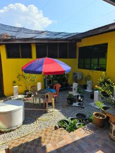 a patio with a table and a red and blue umbrella at Homestay Mamatok B in Kampong Kebun Tok Salim