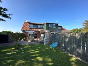 een huis met een hek en een stoel in de tuin bij "Huus ant Diek", Ferienhaus mit Maisonette Wohnung in Deichnähe, Nähe Norddeich in Norden