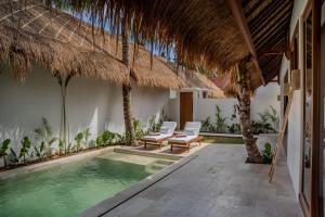 a swimming pool in a villa with a thatched roof at Flora Villa Priv Pool By Yemaya in Kuta Lombok