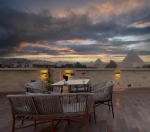 a table and chairs on a roof with pyramids in the background at Pyramids Glory Inn in Cairo