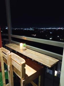 a wooden table and chair on a balcony at night at Stefan's Cozy Place in Agus