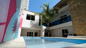 a swimming pool in front of a building with a palm tree at Hotel Casa Bellamare in Cartagena de Indias