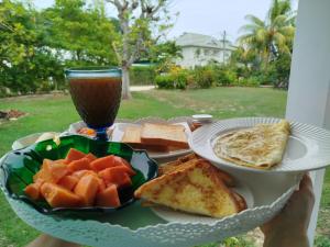a person holding a tray with a plate of breakfast food at Lucy's guesthouse in La Digue +16 photos