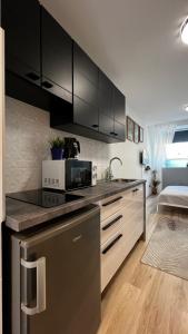 a kitchen with black cabinets and a microwave at Westend - studio above the city in Budapest