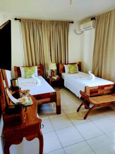 a bedroom with two beds and a table and a chair at Lucy's guesthouse in La Digue