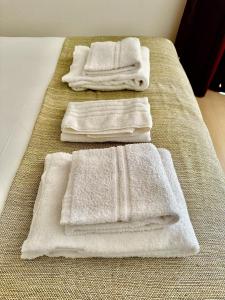 four white towels sitting on top of a bed at Diac Hotel L'Hermitte Bordeaux in Bordeaux