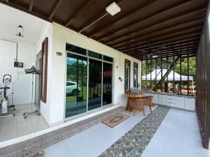 a porch of a house with a table and windows at HOMESTAY JERAI GEOPARK in Guar Chempedak