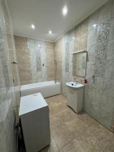 a bathroom with a tub and a sink and a toilet at Трехкомнатная просторная квартира 137 кв центре возле ТЦ Infinity Mall in Atyraū