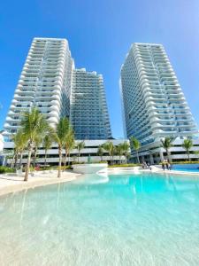 two tall buildings with palm trees in front of a swimming pool at Studio in Azure North Pampanga in San Fernando