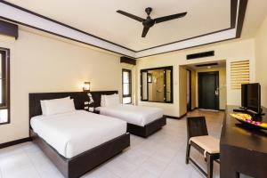 a bedroom with two beds and a desk and a television at Nang Thong Beach Resort in Khao Lak
