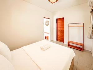 a white bedroom with a white bed with a wooden door at Private Pool Villa Retreat NAMU new one-bedroom 6unit in Kuta Lombok +35 photos