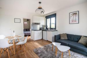 a living room with a couch and a table and chairs at T2 clinique croix du sud climatisé parking lit bultex in Balma