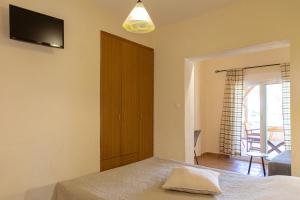 a bedroom with a bed and a tv on the wall at Elenas Beach Studios in Vourvourou