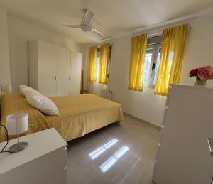 a bedroom with a bed and two windows with yellow curtains at La Casa de la Luz en la Subbética in Carcabuey +22 photos