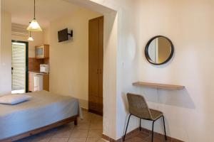 a bedroom with a bed and a mirror and a chair at Elenas Beach Studios in Vourvourou