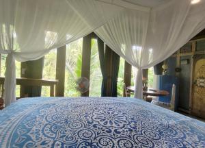 a blue and white bed in a room with a window at Villa Batari - Artsy Joglo - Private Swimming Pool in Tegalalang