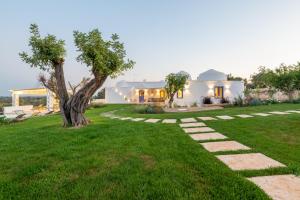 a backyard with a tree and a house at Tenuta PANORAMICAPULIA - Luxury Masseria Ostuni in Ostuni