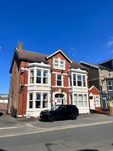 ブラックプールにあるNew Luxury apartment, sea viewWith parkingのレンガ造りの建物の前に停まった黒車