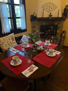 een eettafel met rode servetten en een open haard bij Guesthouse Filokalia in Portariá