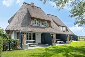 a thatch roofed house with benches in front of it at Beach Lodge Beach Lodge Appartement 1 in Böhl