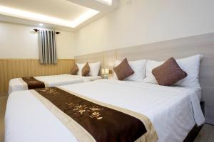 two beds in a hotel room with white sheets at Khanh Lai Hotel 慶來旅店 in Ho Chi Minh City