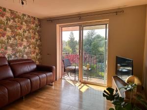 a living room with a leather couch and a balcony at Belfast Skyline Retreat - 3 Bedroom Apartment with Free Parking in Belfast
