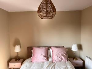 a bedroom with a bed with pink pillows and a lamp at Belfast Skyline Retreat - 3 Bedroom Apartment with Free Parking in Belfast