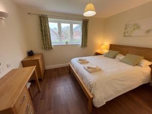 a bedroom with a bed and a desk and a window at Cottages by the Moat in Hassocks