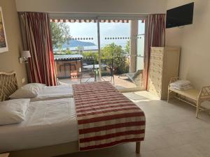 a bedroom with a bed and a view of a patio at Hôtel La Flore in Villefranche-sur-Mer