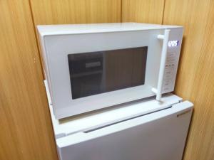 a microwave sitting on top of a refrigerator at SECRET BASE Station Side in Osaka