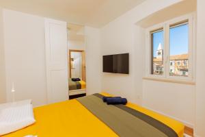 a bedroom with a yellow bed and a tv at Old Charming House in Lastovo