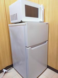 a microwave sitting on top of a refrigerator at SECRET BASE Station Side in Osaka