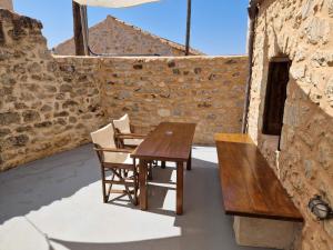 a wooden table and chairs in front of a stone wall at Krialianika House in Areopoli