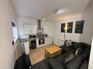 a living room with a couch and a kitchen at Modern 1 Bedroom Apartment with Free Parking Near the M6 and Birmingham in Wednesbury