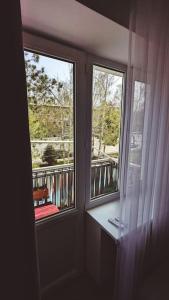 a room with two windows and a red chair on a balcony at Cozy apartment in the city center of Karakol in Karakol +2 photos