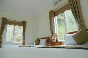 a bedroom with two beds and two windows at Gold Plus hotel in Phong Nha