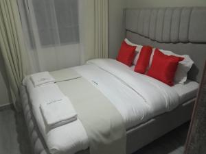 a white bed with red pillows in a room at Weber Generations Accommodation -R & R Cozy Homes in Naivasha