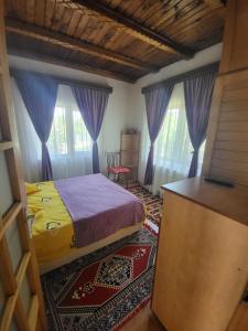 a bedroom with a bed and two windows with purple curtains at Casa Roza in Breaza de Sus