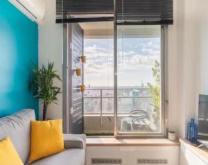 een woonkamer met een bank en een groot raam bij Cocon design et cosy à La Défense, vue imprenable sur Paris in Puteaux