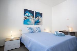 a bedroom with a bed with two paintings on the wall at Senza Pensieri Holiday Home in Balestrate
