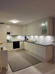 a kitchen with white cabinets and a sink at Rom til leie i Tromsø - nært alt - flott standard in Tromsø