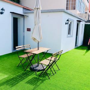 a table and chairs with an umbrella on a lawn at Casa D'Avó Filó in Funchal