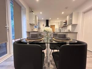 a dining room with a glass table and black chairs at Comfortable 3 bed house in central location, Stevenage in Stevenage