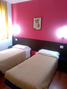 dwa łóżka w pokoju z różową ścianą w obiekcie Hotel motel residence Gonzaga w mieście Cantello